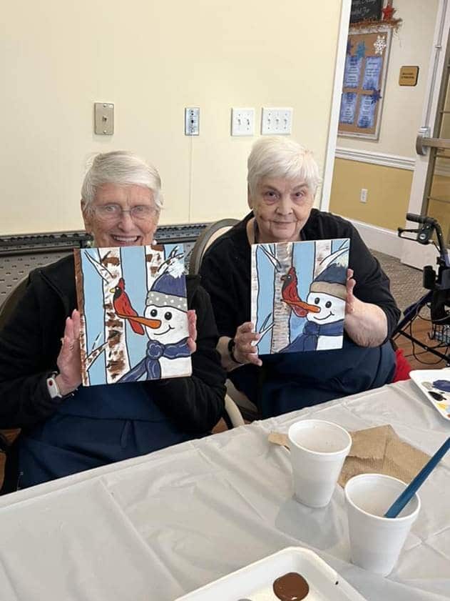 2 ladies showing their artwork